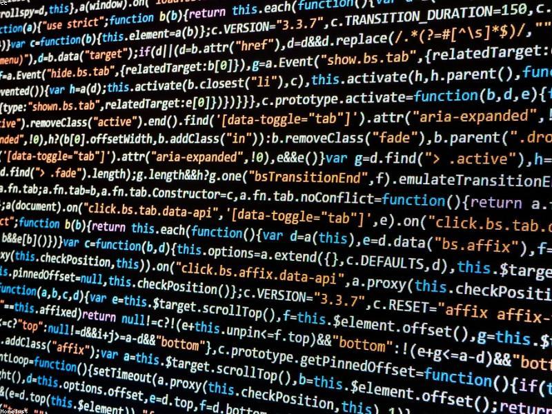 Developer writing code on multiple monitors with dark themed IDE